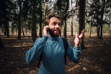 Young adult man talking on the phone standing over white brick wall stressed with hand on head, shocked with shame and surprise face, angry and frustrated.