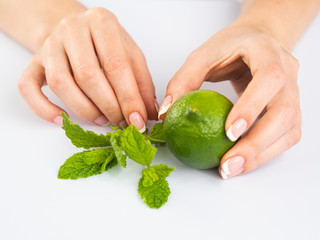 Female Hands with French Manicure on Nails Holding a Fresh Summer Limet and Mint Leaves. Summer Freshness concept