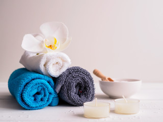 Obraz na płótnie Canvas Wellnessbehandlung, Handtücher und Teelichter auf einem weißen Hintergrund, Orchidee