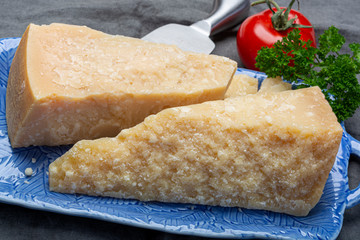 Italian original aged Parmesan cheese in two pieces served on blue plate close up