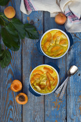 Clafouti with apricots in rameken on blue wooden background. Fruits clafoutis. Sweet casserole. Traditional French cake. Copy space
