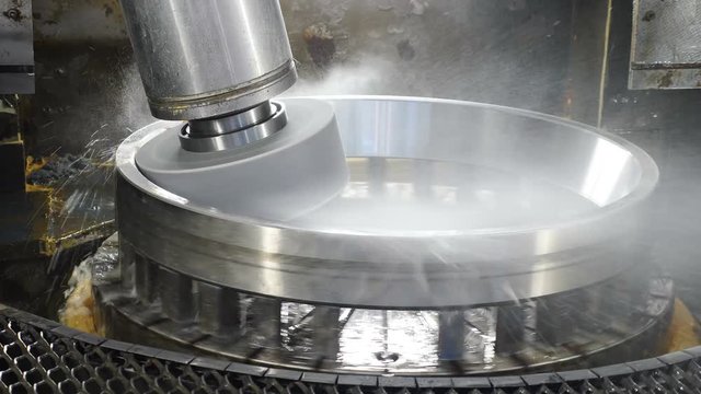 Industry concept. Grinding wheel disk polishing metal surface on bearings manufacture. Rolling mill machine with cooling water splashing. Technological part of fully automatical bearing assembling