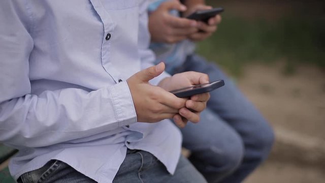 Close up of Young boy sitting on the bench and play online games during school break