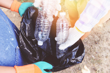 Group of young women volunteers helping to keep nature clean and picking up the garbage plastic bottle from park - Recycling and waste reduction techniques that help the environment