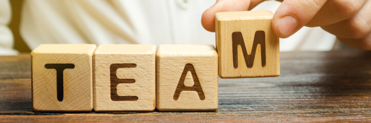 Businessman holds wooden blocks with the word Team. Team management concept. Teamwork. Hiring....