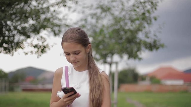 Young girl use phone during school break. Girl play online games