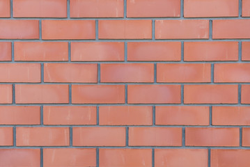 Orange-red brick wall close-up with stitching. Wall texture in grunge style. Brick background for a subject shooting a flat lay. Concept of construction and interior design. Copy space