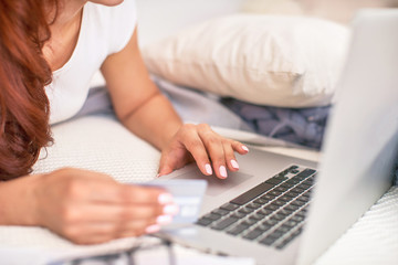 the student is happy to communicate with friends via the Internet. home schooling, work and study, new knowledge.happy teen on bed with computer. girl student lying on the bed smiling.