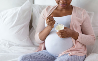 pregnancy, people and rest concept - close up of happy pregnant african american woman eating...