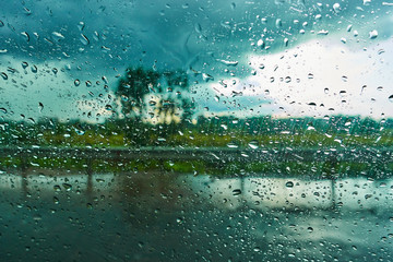 Blurred background with rain drops on car glass. Riding in the rain