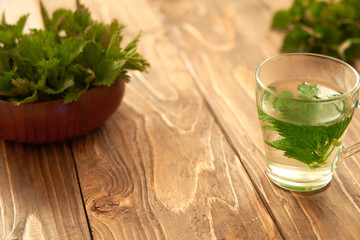 on a wooden background is a glass with brewed young nettles. medicinal broth of nettle. vitamin herbal tea.