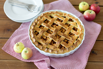 food, culinary and baking concept - apple pie and kitchen towel on wooden table