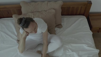 Reflective young woman between 30 and 35 years old stays in her bed.