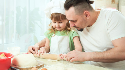 father preparing food with my daughter. a man teaches a child to cook. the process of cooking in a bright kitchen. home cooking is the father of one daughter and love to cook
