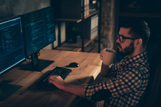 Close up side profile photo handsome mug hot beverage he him his guy coder typing php css keyboard development outsource IT processing two monitors table office agency wear specs formalwear shirt