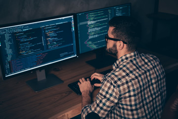 Close up back rear behind photo handsome he him his guy typing writing keyboard development outsource IT processing language two monitors table office wear specs formalwear plaid shirt
