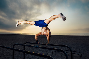 fitness, sport, training, calisthenics and lifestyle concept - young man exercising handstand on bar outdoors