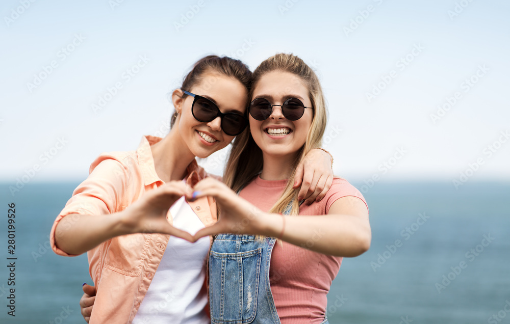 Wall mural leisure and friendship concept - happy smiling teenage girls or best friends in sunglasses at seasid