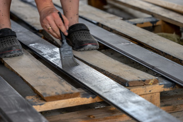 Painting boards with a brush held in hand. Gray, anthracite wood paint.