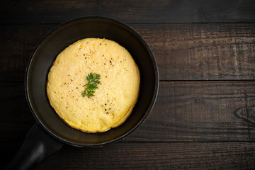 omelet in a pan on a wooden background.