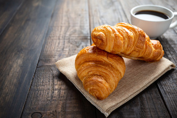 croissants and coffee on old wooden table.