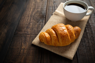 croissants and coffee on old wooden table.