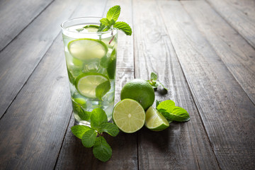 Mojito drink with lime, lemon and mint on wooden table.