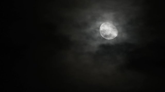 Time lapse motion Craters On The Surface Of The full moon In the dark sky and the black clouds at night Moving up fast.