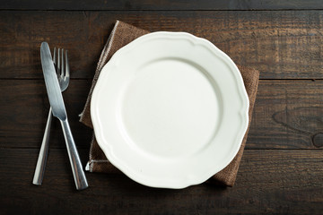 Empty white plate on wooden table.