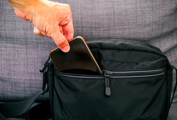 Man hand taking mobile phone from black bag.