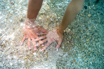 Hands in the water on a sandy beach, tourism, travel concept