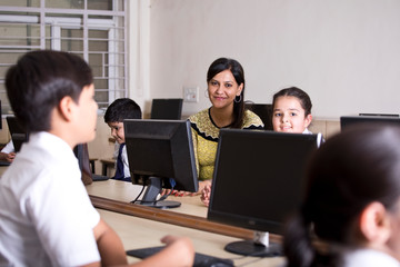 Indian teacher helping students at computer class