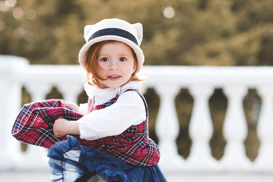 Funny Baby Girl 3-4 Year Old Dancing Outdoors Wearing Dress And Hat Closeu. Looking At Camera.