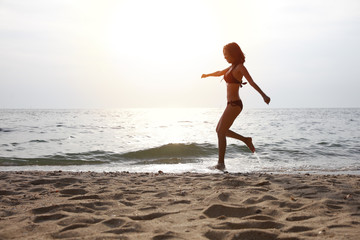 slim healthy woman with bikini running on beach