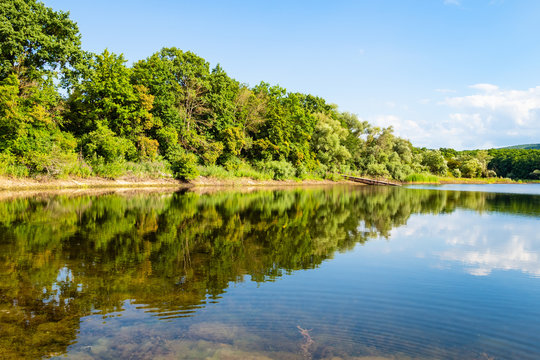 view of karst lake in forest at summer sunset