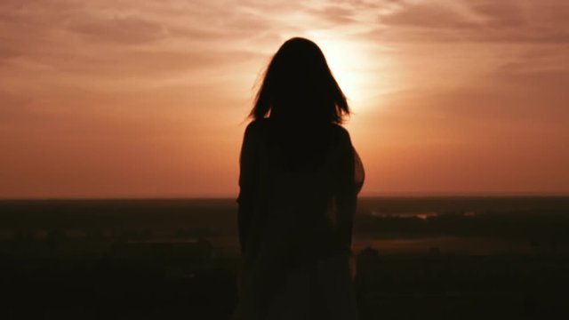 rear back view woman with long hair standing on the hill watching on the sky with dawn sun
