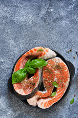 Fresh, raw salmon steak with spices on a stone background. View from above.