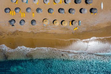 Aerial view of sandy seashore with umbrellas and sun beds 