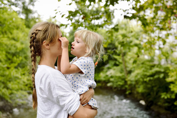 Fototapeta na wymiar Happy Mother and little Daughter outdoor portrait in France. Mom and her child enjoying nature together in the park. Beautiful family. Mother's Day concept