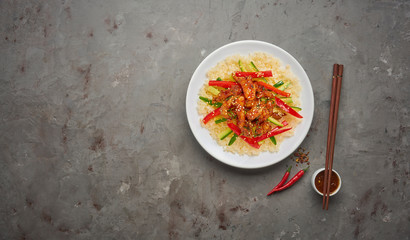 Stir-fry chicken meat, vegetables and rice on grey stone background. Copy space, top view