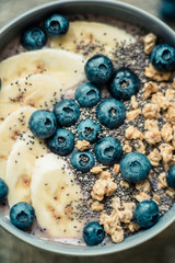 Healthy breakfast berry smoothie bowl topped with banana, granola, Blueberries and chia seeds with copy space