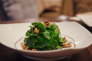 Lettuce salad with walnut and raisin in white plate