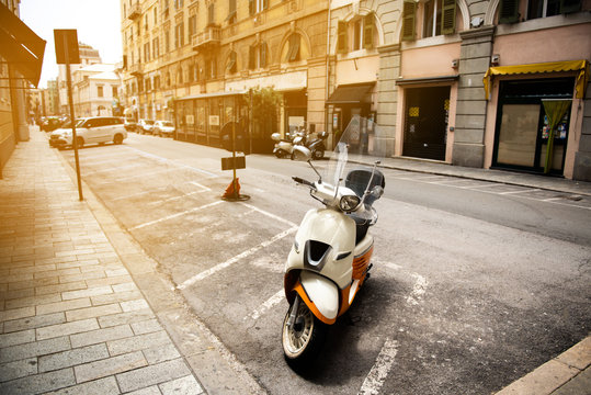 White-orange motor scooter of new design in the urban environment of Italy in the parking lot