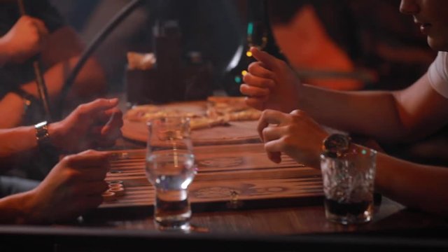 Men friends smoking hookah playing backgammon in a bar