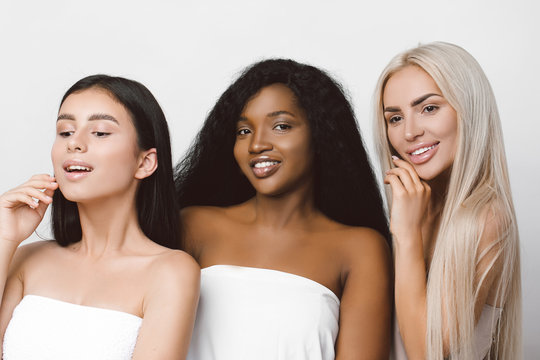 concept of three different ethnicity of women being very close one to each other and posing naked covered with cloth and expressing friendship. Young women with natural make-up and hair style. 