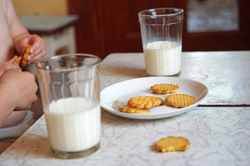 Children eat cookies with milk in glass cups