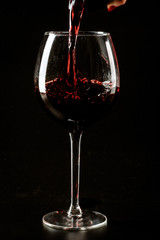 Red wine being poured in a wine glass on a dark background