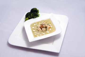 Hero Shot of a Broccoli Soup with bread crumbs, oregano on a minimal white background with a 45 degree front facing angle