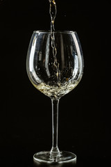 White wine being poured in a wine glass on a dark background