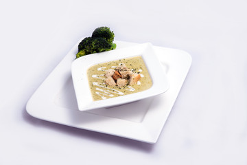 Hero Shot of a Broccoli Soup with bread crumbs, oregano on a minimal white background with a 45 degree front facing angle